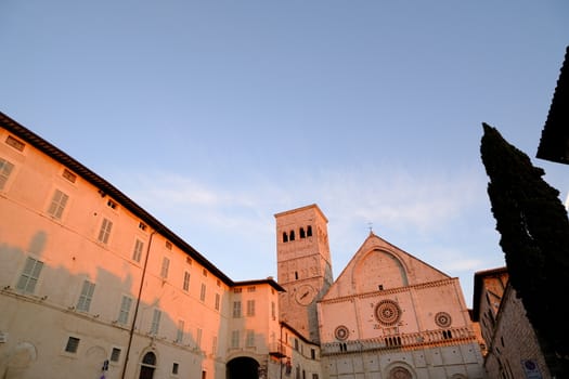 Cathedral of San Rufino in Assisi, facade made of stone with an ogival arch on the triangular tympanum. Photographed at sunset with rosy light.