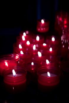 Many burning candles with red plastic sheath. No people