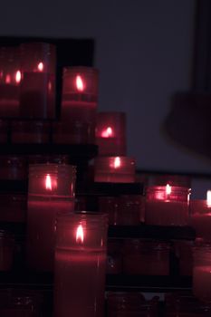 Many burning candles with red plastic sheath. No people