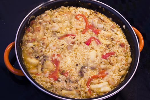 Rice paella cooked with chicken, seafood and vegetables. No people