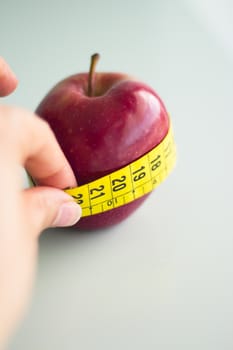 Tape measure surrounding a red apple. Related to a healthy diet