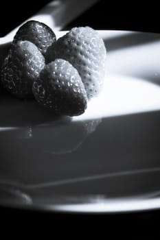 Ripe strawberries on a white plate and dark background. No people