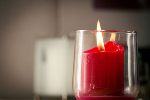Burning red candle inside a clear glass vase. No people