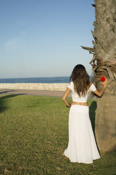 Girl dressed in white with the sea on her back. Tranquil scene