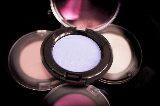 Various makeup shadows on dark background. No people