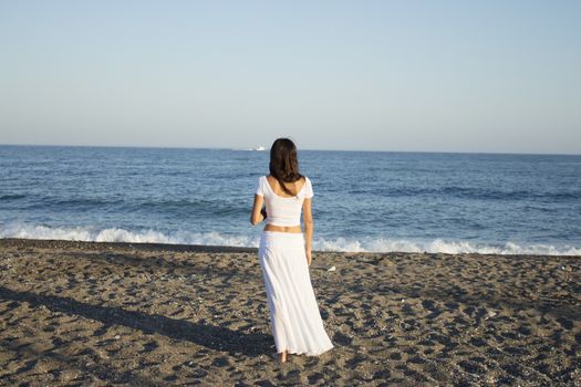 Girl dressed in white with her back to the beach. Tranquil scene