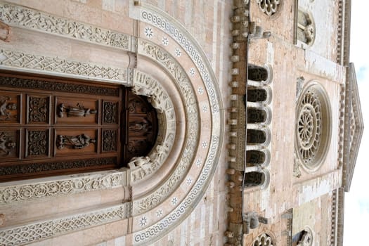 Foligno, Umbria, Italy. About october 2019.  Wooden door portal and carved light marble rosette of the Cathedral of San Feliciano in Foligno.
