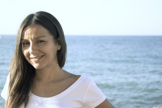 Portrait of young girl dressed in white with the sea in the background