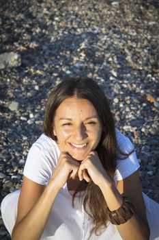 Woman sitting on stones with hands on the pensive face. Positive expression
