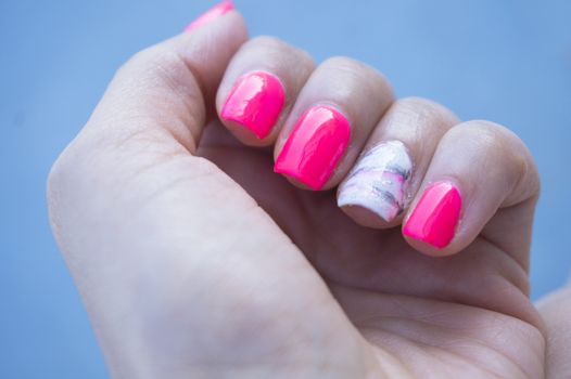Womans hand showing her semipermanent manicure. Pink colour