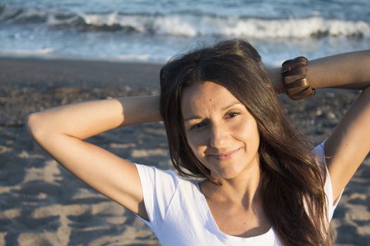 Girl with white t-shirt on the beach and her arms on the neck. Very happy