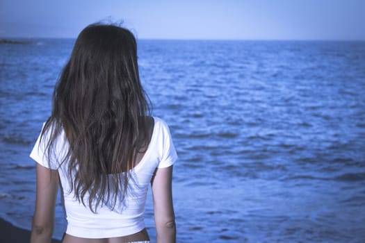 Girl dressed in white with the sea on her back. Tranquil scene
