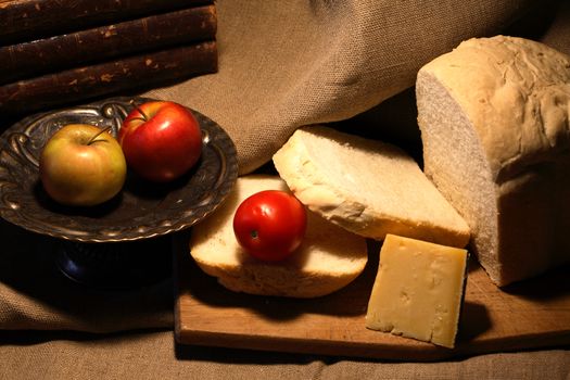 Sliced loaf of white bread near cheese and fruits on canvas background