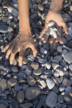 Woman hands touching stones on the beach. Grey stones