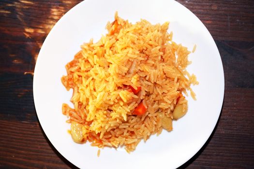 White plate with pilaf portion on wooden table