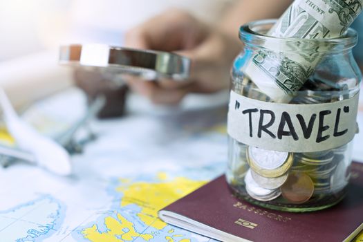 Saving money in a glass jar for travel on map