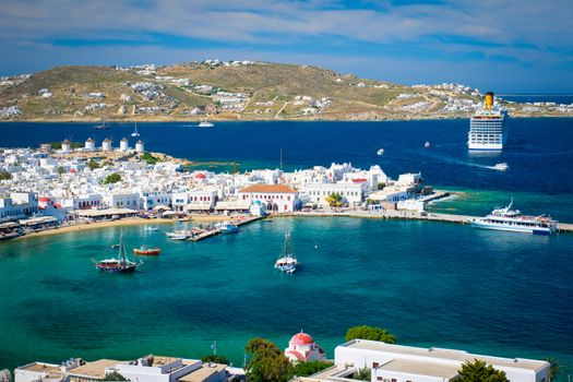 View of Mykonos town Greek tourist holiday vacation destination with famous windmills, and port with boats and yachts. Mykonos, Cyclades islands, Greece