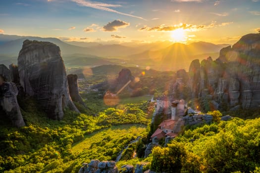 Sunset over monastery of Rousanou and Monastery of St. Nicholas Anapavsa in famous greek tourist destination Meteora in Greece on sunset with sun rays and lens flare