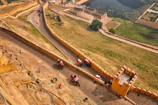 Tourists riding elephants on ascend to Amer (Amber) fort, Rajasthan, India. Amer fort is famous tourist destination and landmark