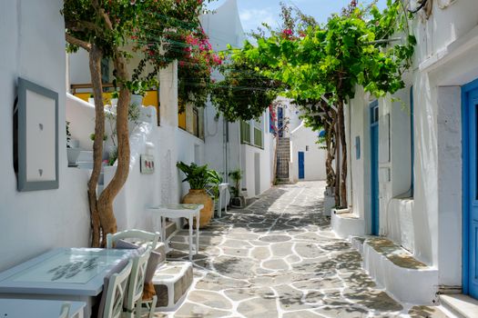 Picturesque narrow street with traditional whitewashed houses with cafe tables of Naousa town in famous tourist attraction Paros island, Greece