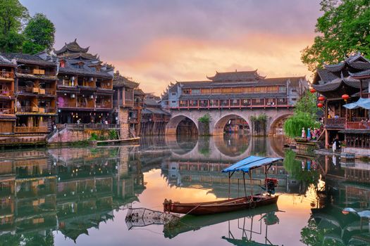 Chinese tourist attraction destination - Feng Huang Ancient Town (Phoenix Ancient Town) on Tuo Jiang River illuminated at night. Hunan Province, China