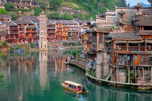 Chinese tourist attraction destination - Feng Huang Ancient Town (Phoenix Ancient Town) on Tuo Jiang River with Wanming Pagoda tower and tourist boat. Hunan Province, China