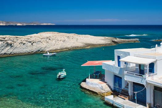 Greece scenic island view - small harbor with fishing boats in crystal clear turquoise water, traditishional whitewashed house. MItakas village, Milos island, Greece.