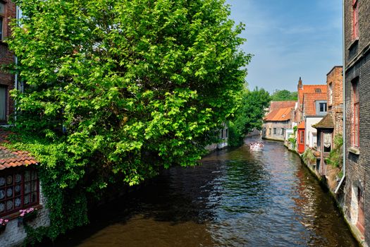 Tourist boat in canal between old houses of famous Flemish medieval city Brugge. Bruges, Belgium