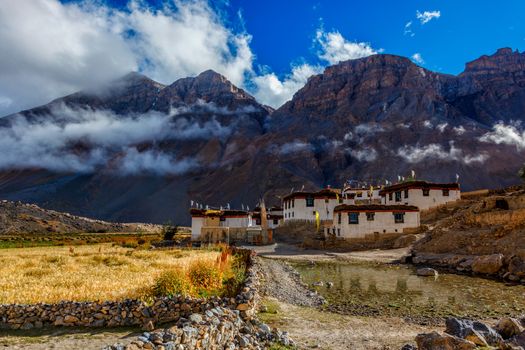 Himalayan landscape with high altitude village in Spiti Valley aslo known as Little Tibet. Whitewashed houses stand just below clouds surrounded by Himalaya chain of mountains. Himachal Pradesh, India