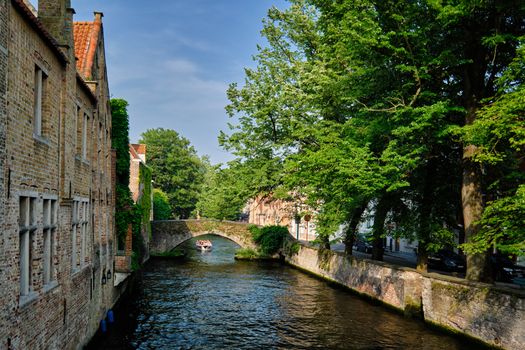 Tourist boat in canal between old houses. Brugge Bruges, Belgium