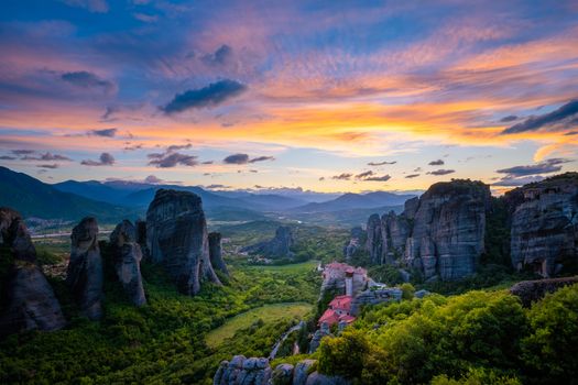 Sunset sky and monastery of Rousanou and Monastery of St. Nicholas Anapavsa in famous greek tourist destination Meteora in Greece with sun rays and lens flare