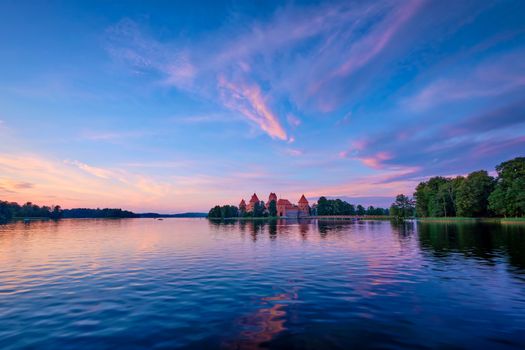 Trakai Island Castle in lake Galve, Lithuania on sunset with dramatic sky reflecting in water. Trakai Castle is one of major tourist attractions of Lituania, now museum and cultural center. Europe