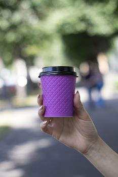Purple cardboard Cup for coffee in a woman's hand