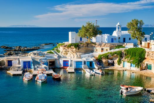 Typical Greece scenic island view - small harbor with fishing boats in crystal clear turquoise water, traditional white houses church. Mandrakia village, Milos island, Greece.