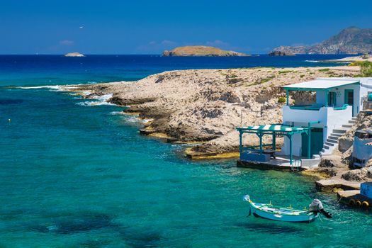 Greece scenic island view - small harbor with fishing boats in crystal clear turquoise water, traditishional whitewashed house. MItakas village, Milos island, Greece.