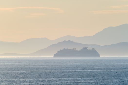 Cruise liner ship silhouette in haze in Mediterranea sea. Aegean sea, Greece