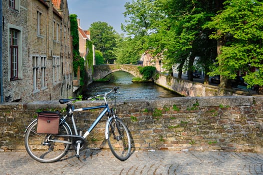 Typical Belgian scenic cityscape Europe tourism and bicycle transport concept - bicycle on a bridge near canal and old house. Bruges (Brugge), Belgium