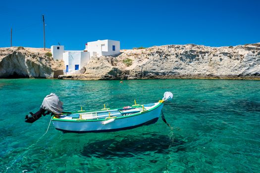 Greece scenic island view - small harbor with fishing boats in crystal clear turquoise water, traditishional whitewashed house. Mitakas village, Milos island, Greece.