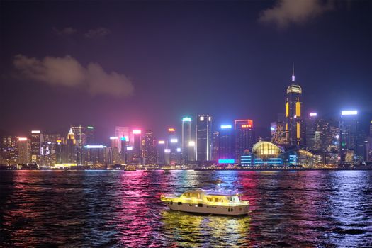 Hong Kong skyline cityscape downtown skyscrapers over Victoria Harbour in the evening illuminated with tourist boat ferries . Hong Kong, China