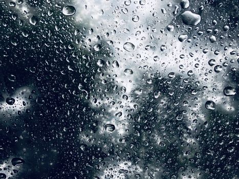 Water drops on glass with blurred scenic view in the background