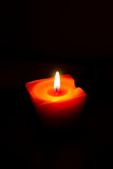 Closeup of burning candle isolated on black background.