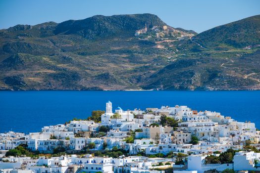 View of Plaka village with traditional Greek orthodox church and white painted houses and ocean coast. Milos island, Greece