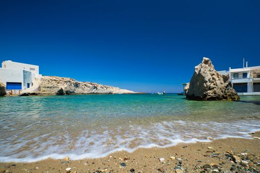 Greece scenic island view - small harbor with fishing boats in crystal clear turquoise water, traditishional whitewashed house. MItakas village, Milos island, Greece.