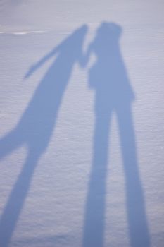 Holding hands creating a shadow in the snow. Shadows of people in the snow