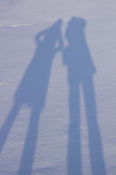 Holding hands creating a shadow in the snow. Shadows of people in the snow