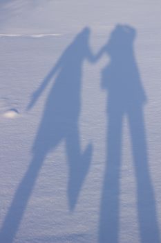 Holding hands creating a shadow in the snow. Shadows of people in the snow