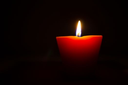 Closeup of burning candle isolated on black background.