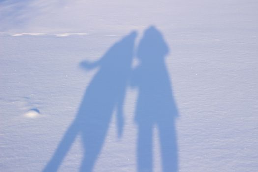 Holding hands creating a shadow in the snow. Shadows of people in the snow