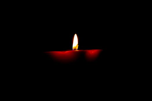 Closeup of burning candle isolated on black background.