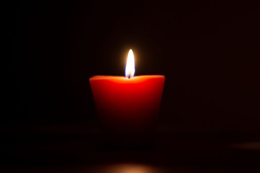 Closeup of burning candle isolated on black background.